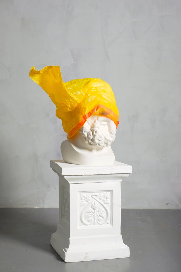 A classic sculpture covered with a yellow plastic bag symbolizing modern environmental challenges.